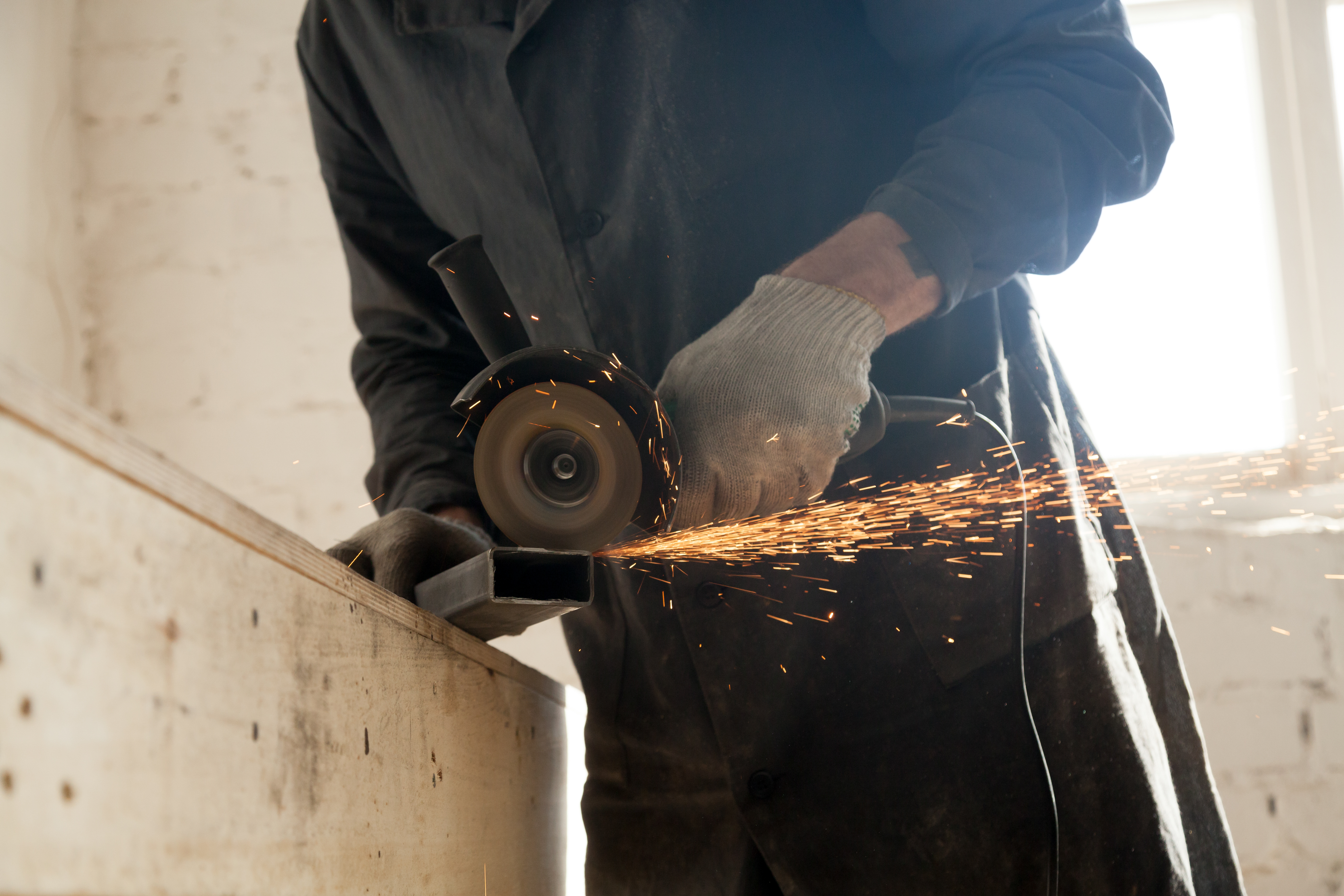 Worker grinding metal with sparks flying.